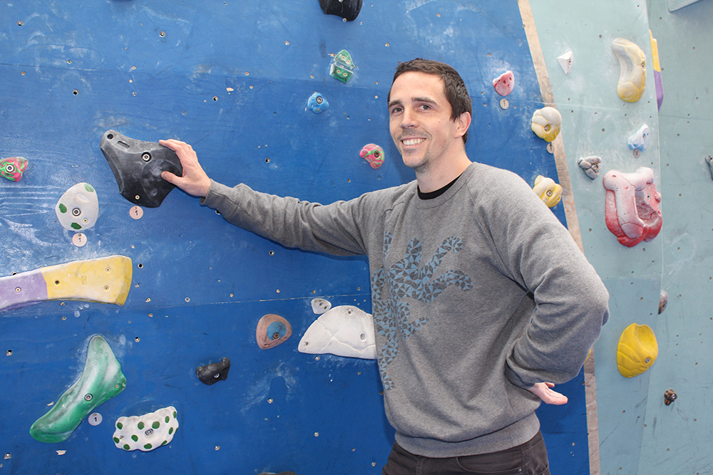 red Stone founder of The Arch standing in front of a climbing wall in the Biscuit Factory at Workspace®.