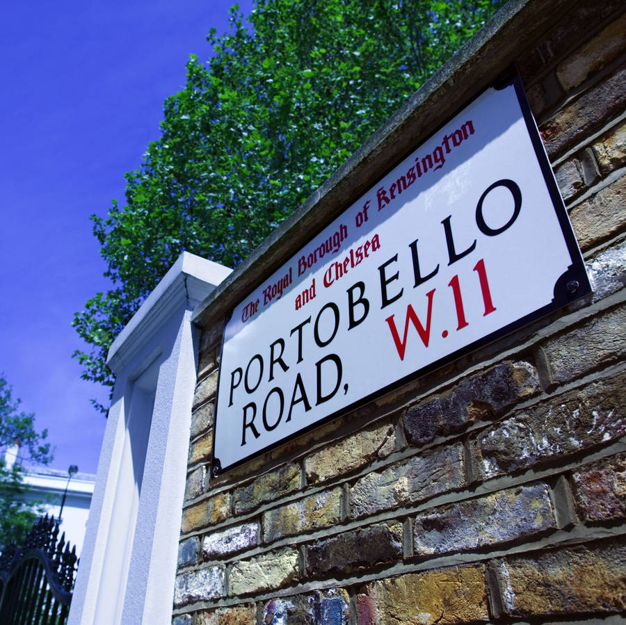A street sign for Portobello Road on a brick wall.