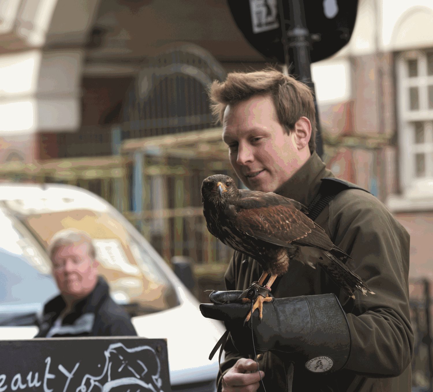 A person with a bird of prey standing on their arm.