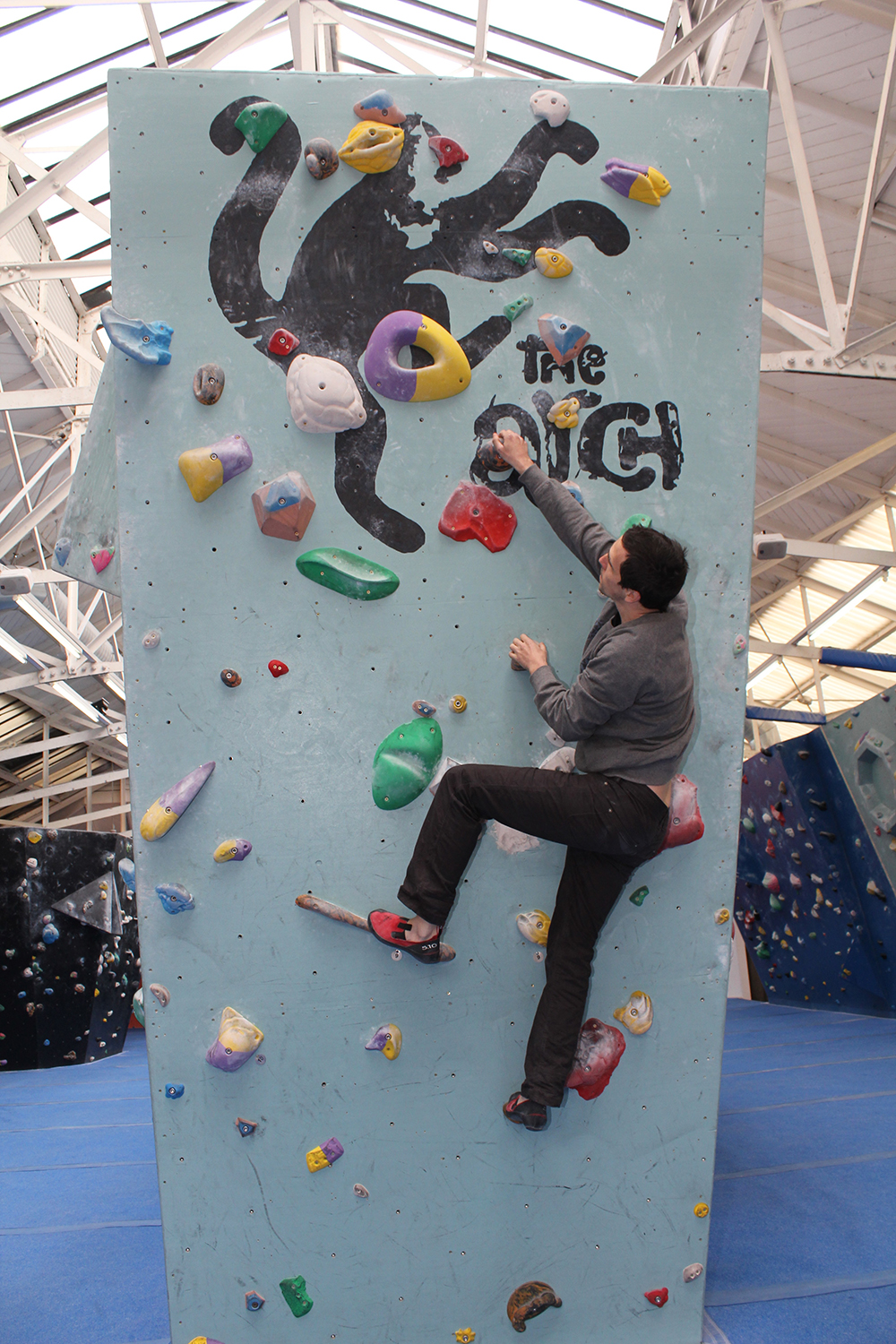 Fred Stone founder of The Arch standing climbing a climbing wall in the Biscuit Factory at Workspace®.